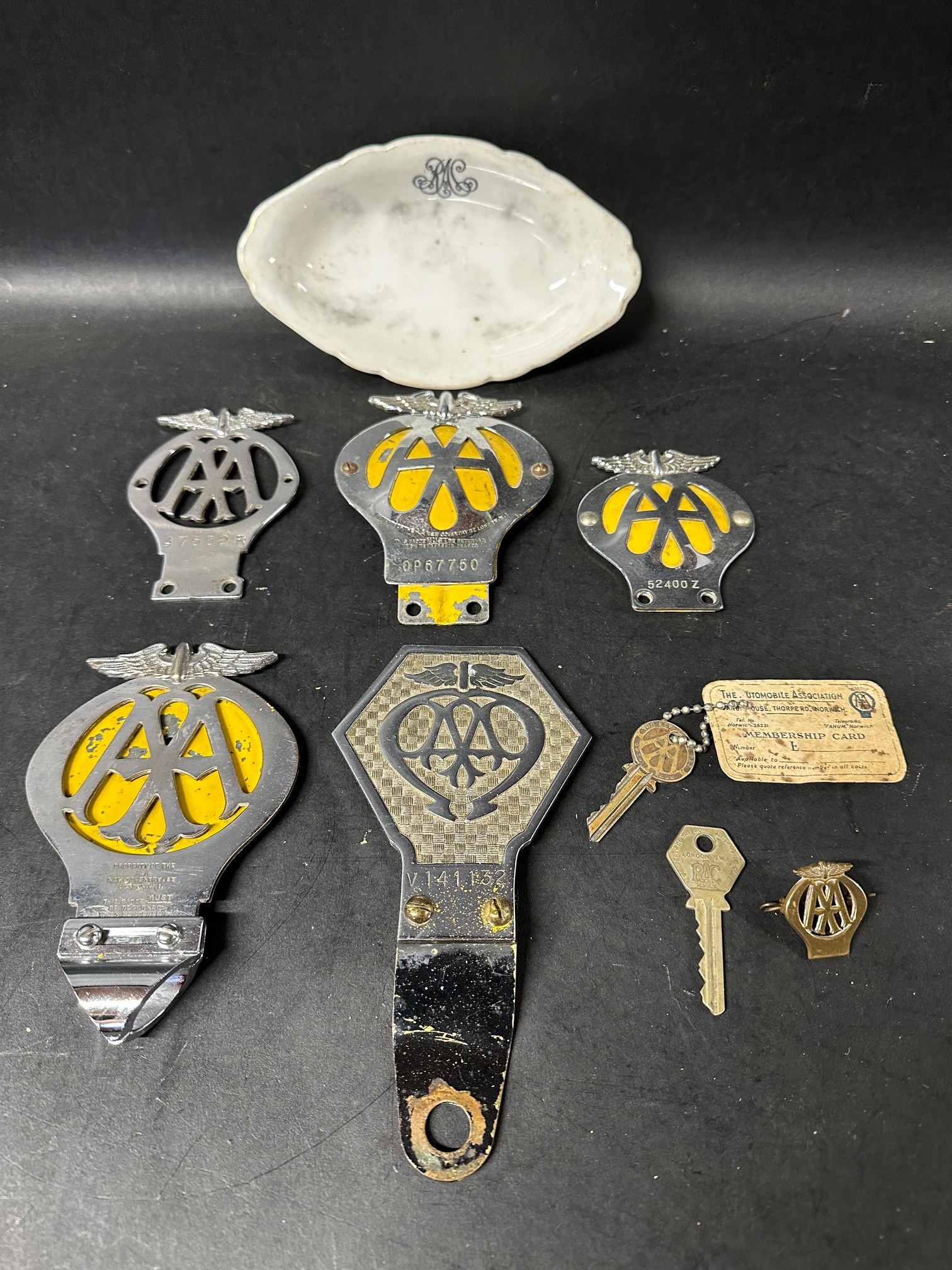 A group of AA car badges, keys, a cap badge and an RAC dish.
