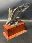 A car accessory mascot in the form of an egale perched on a rock, wooden display base mounted. A