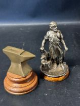 A brass macot in the form of an anvil and a Vulcan car accessory mascot in the form of a blacksmith,