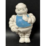 A 1930's Michelin Tyres promotional squeaky toy figure of Mr. Bibendum in a bib clutching a toy Mr