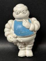 A 1930's Michelin Tyres promotional squeaky toy figure of Mr. Bibendum in a bib clutching a toy Mr