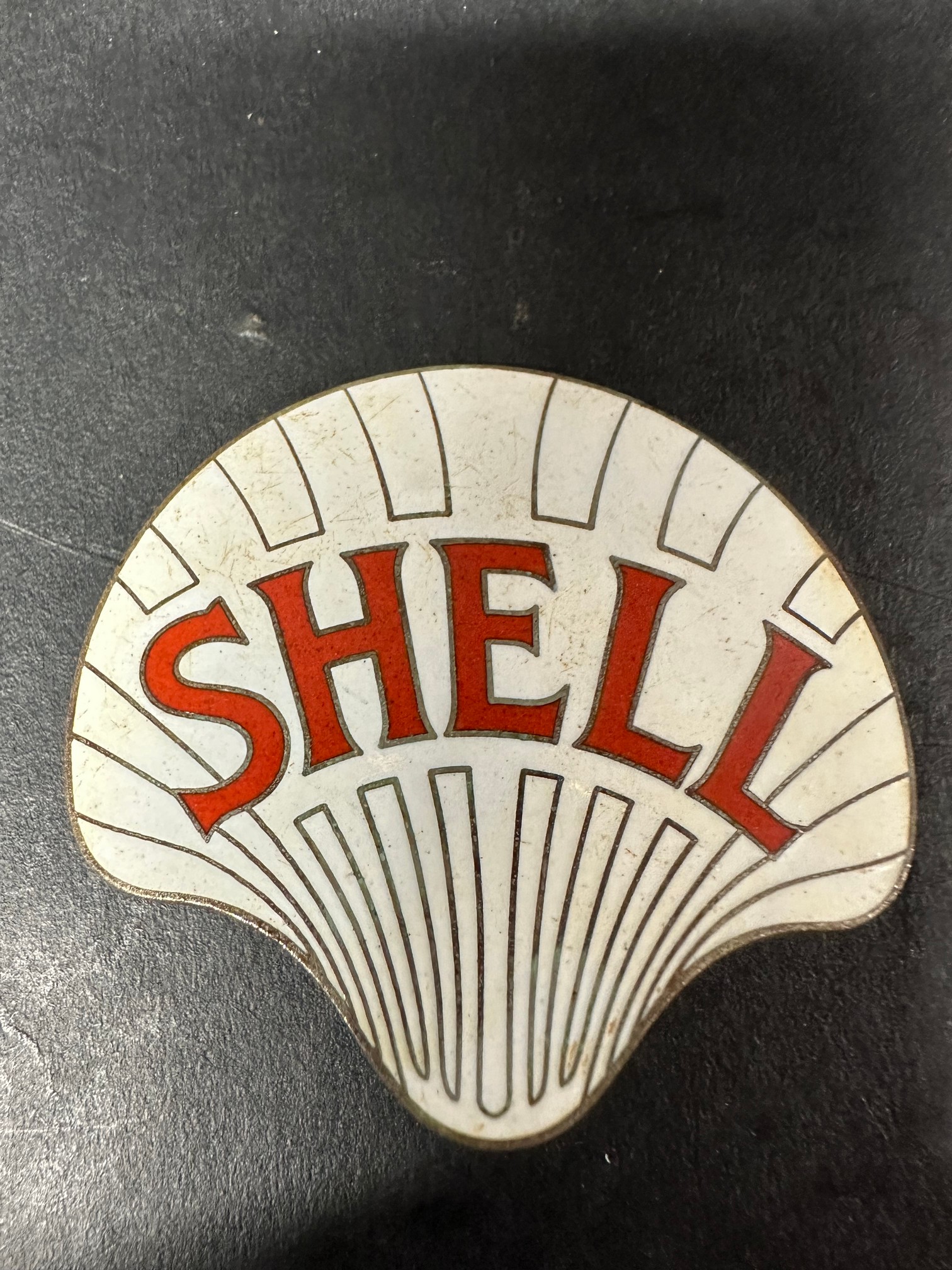 A large Shell enamel cap badge.