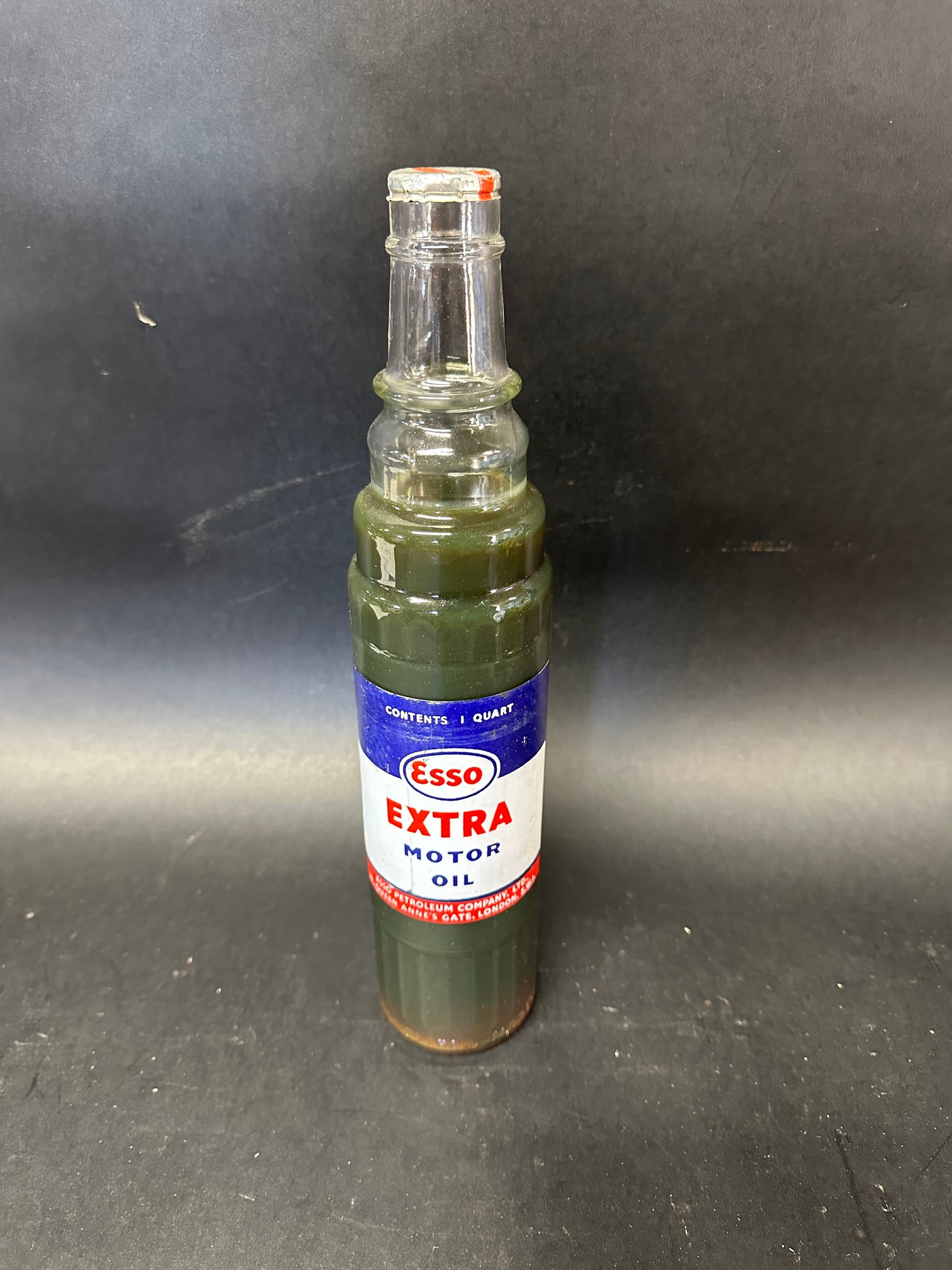 An Esso Extra Motor Oil glass quart bottle with foil top.