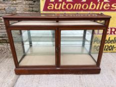 A glass display cabinet with two front opening doors and two hinged front uplifting openings, with