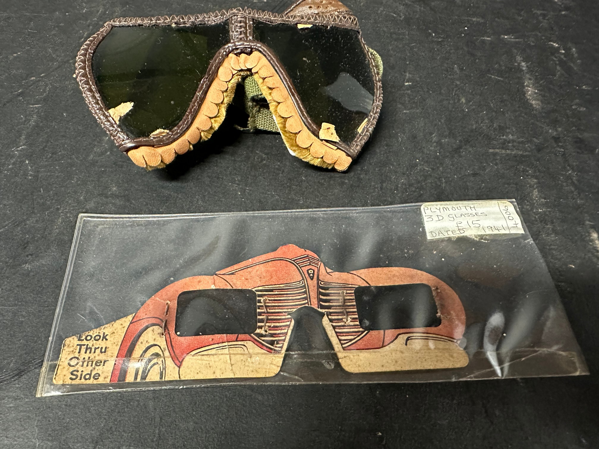 A pair of U.S. goggles, dated 1944 and a Plymouth Polaroid viewer in the form of a Plymouth car,