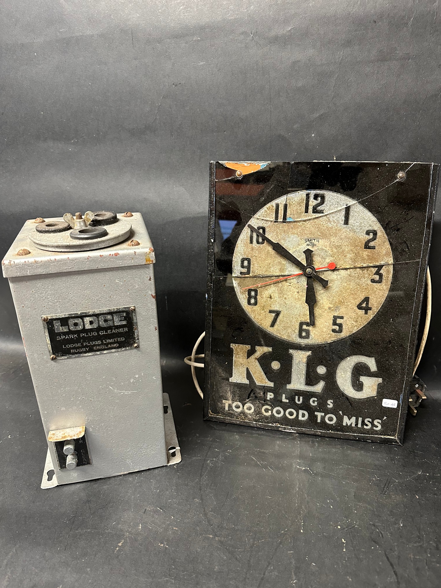 A K.L.G Plugs Smith sectric wall clock (see damage in images) and a Lodge Spark Plug Cleaner.