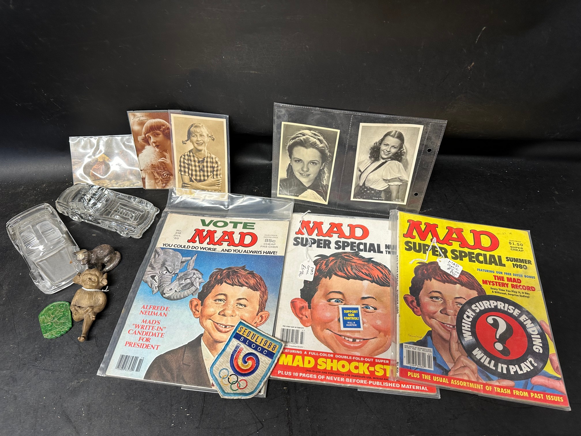 Three 1980s MAD comics, a selection of postcards, a Lincoln Imp, glass model cars etc.