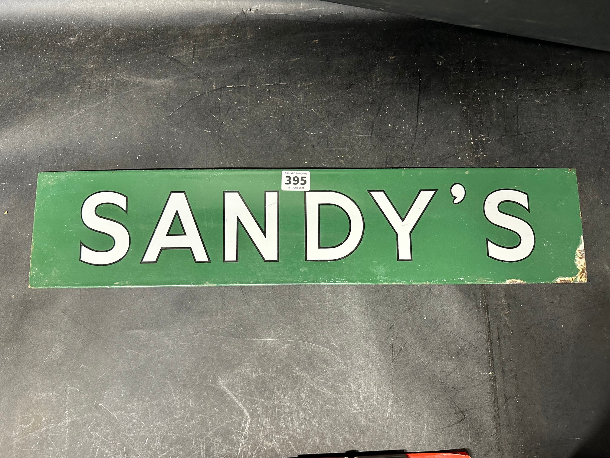 An enamel sign for 'Sandy's', 23 1/2 x 5".