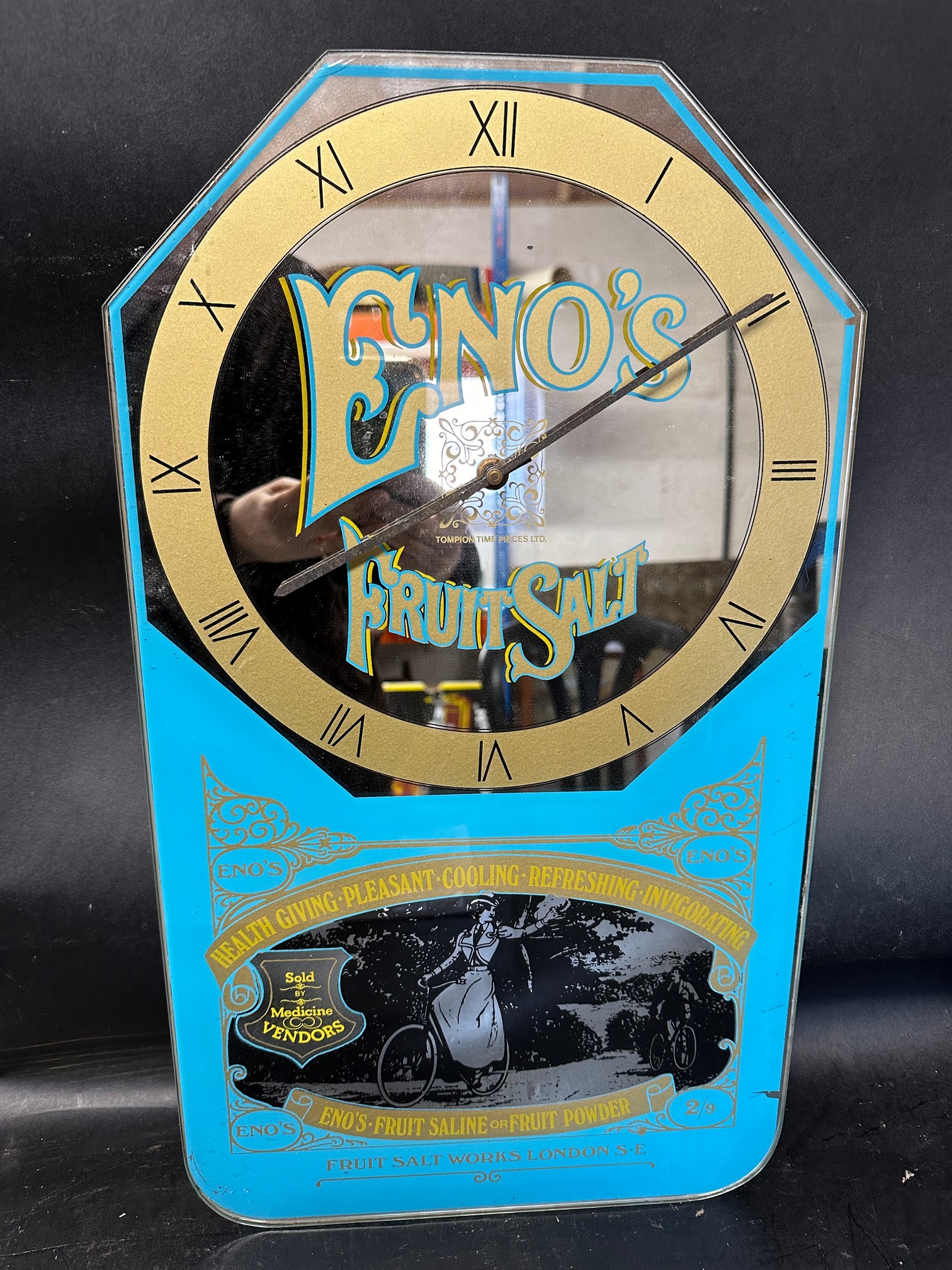 A mirrored advertising wall clock for Eno's Fruit Salt of London with image of cyclists to bottom
