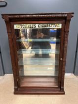 A counter top cabinet bearing the advertising for Mitchell's Cigarettes, front opening, key to
