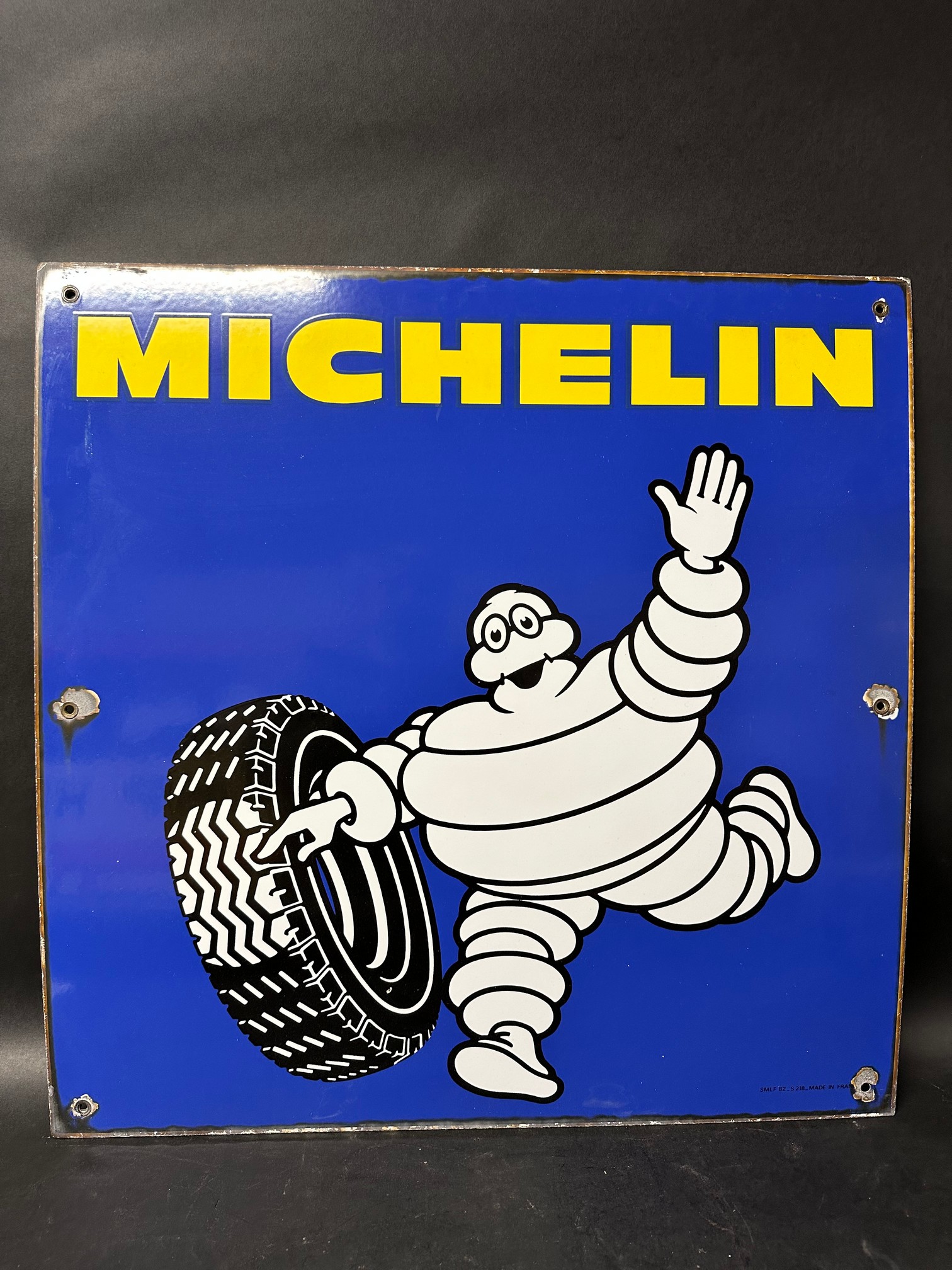 A Michelin single sided enamel sign depicting Mr Bibendum rolling a tyre made in France 1982, 25 3/