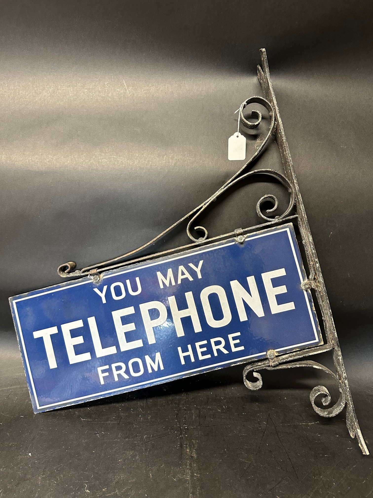 A 'You May Telephone From Here' double sided enamel sign set within a wall mounting bracket, 11 x