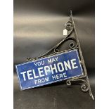 A 'You May Telephone From Here' double sided enamel sign set within a wall mounting bracket, 11 x