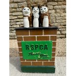 An RSPCA charity donation box with three cats upon a wall behind three milk bottles, with carry