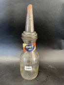 An American glass quart oil bottle with grade band on the neck and tin spout.