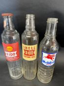 Three glass quart oil bottle: Shell X-100 with lid, another Shell X-100 and a Mobiloil Vacuum.