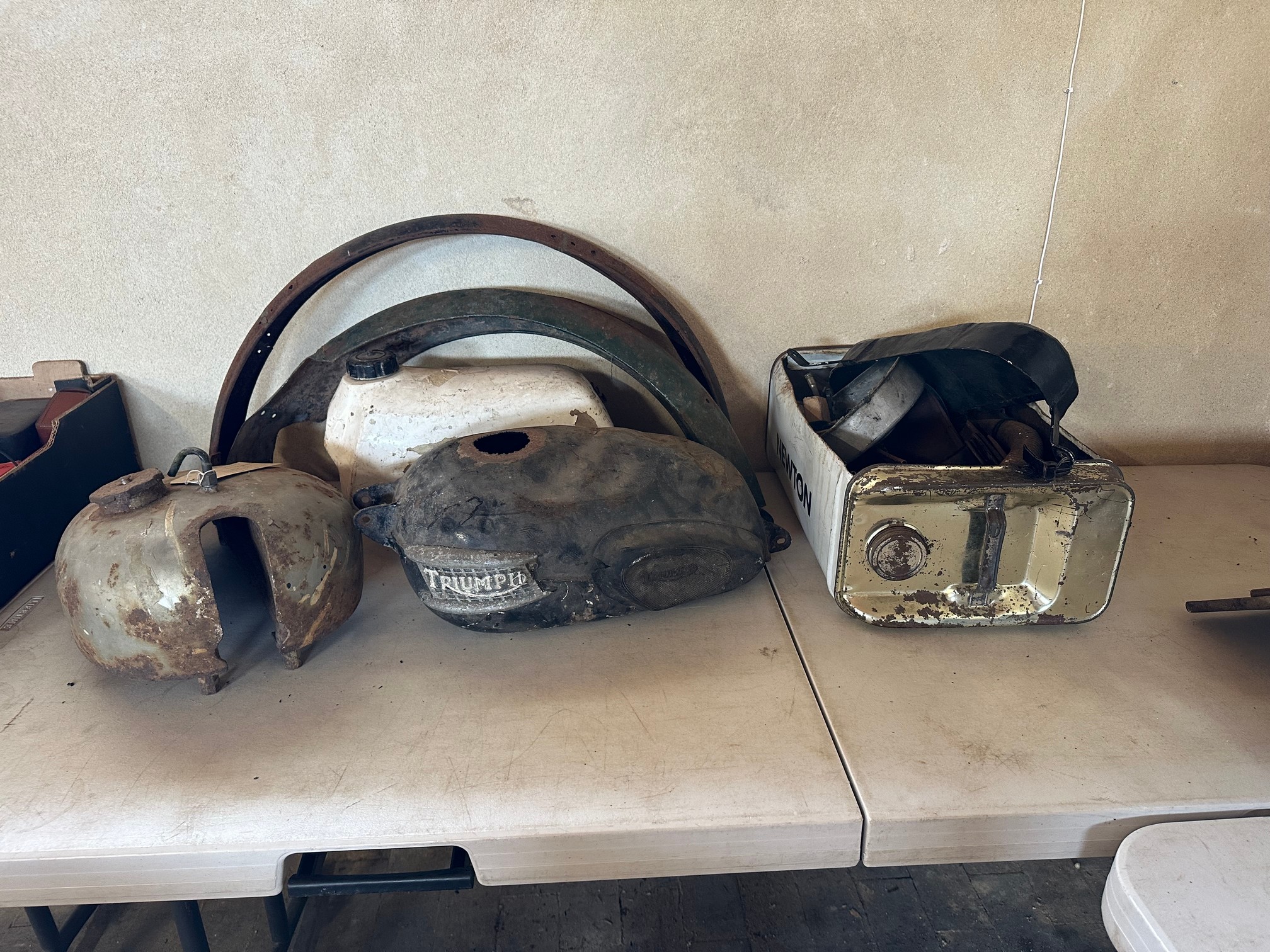 Three old fuel tanks including Triumph, two mudguards and quantity of spare parts etc.