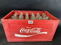 A Coca-Cola bottle crate containing 24 Coca-Cola drinks bottles, 15 1/2 x 10 1/2
