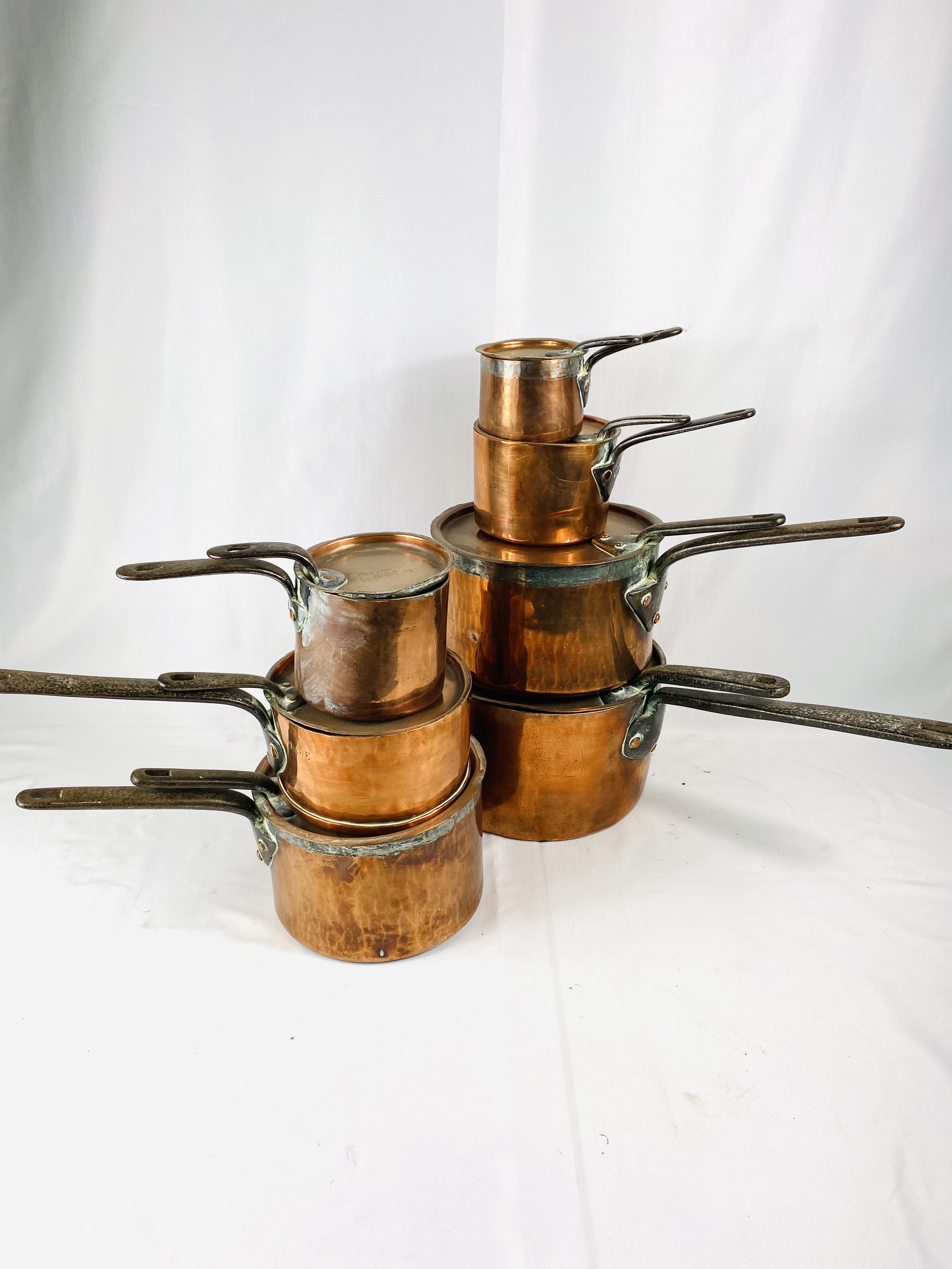 Seven Victorian tin lined copper saucepans with lids