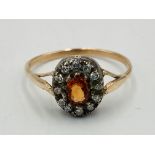 Orange stone ring with diamond surround