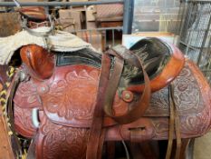 21" western saddle with pair of stirrups and spurs, with leather straps and ropes.