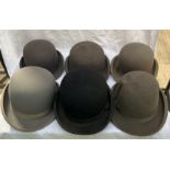 Five grey bowler hats and a black bowler hat