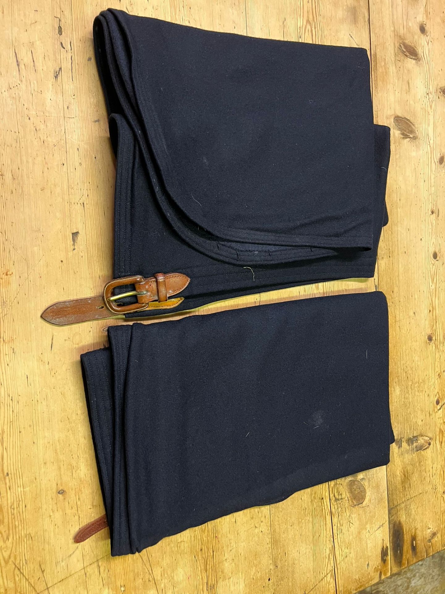 Pair of dark blue Melton cloth aprons, one with an antique leather covered buckle