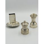 Two silver pepper grinders together with a silver matchbox holder