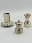 Two silver pepper grinders together with a silver matchbox holder