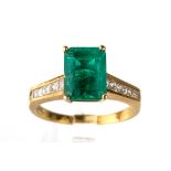 An 18k yellow gold emerald and diamond ring, the step-cut emerald approx 9.5mm x 7mm, in four