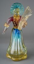 A Murano glass figure of a lady wearing bonnet and carrying bread, in clear with gold powders and
