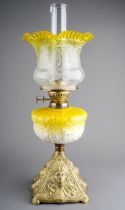A Victorian style gilt metal oil lamp, the yellow resevoir moulded with scrolling flowers, with