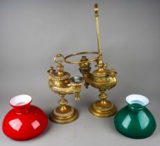 A matched pair of German Wild & Wessel 1373 Aladdin style brass table lamps, with red over white