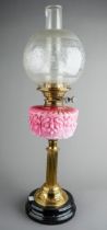 A Victorian style brass oil lamp on reeded column base, with pink moulded glass reserve, etched