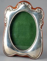 An Edwardian style silver mounted oak photograph frame, the shaped silver border with embossed