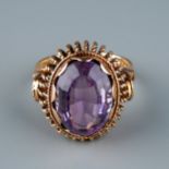 A 9ct gold and amethyst dress ring, the large oval mixed-cut amethyst in rub-over settings, rope-
