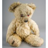 A 1930's Merrythought teddy bear, with blonde mohair, one orange and black glass eyes, black