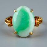 A 14k yellow gold and jade ring, set with an oval cabochon stone in four claw settings, detailed
