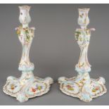 A pair of KPM Berlin candlesticks in the 18th Century Rococo manner, painted with flowers and