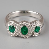 An 18ct white gold emerald and diamond ring, set with three oval-cut emeralds within borders of