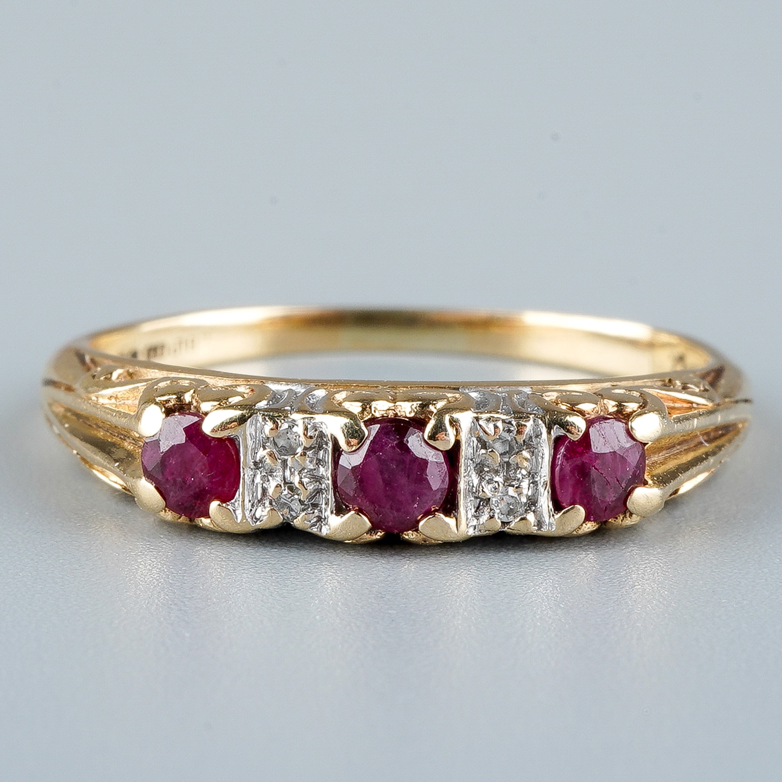 A 9ct yellow gold ruby and diamond ring, set with three round-cut rubies with diamond-chip