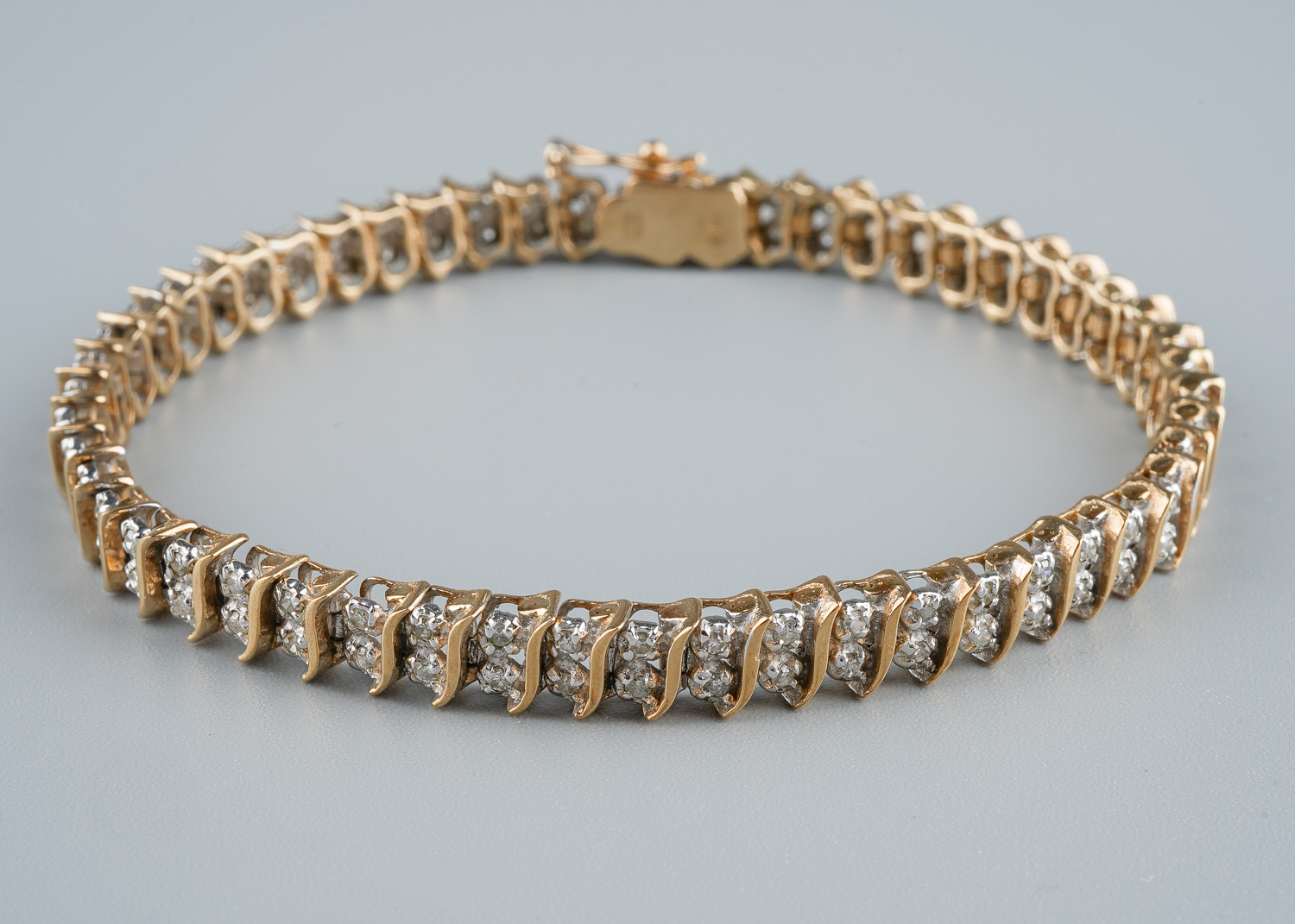 A 9ct gold and diamond line bracelet, with two round brilliant-cut diamond set links between S