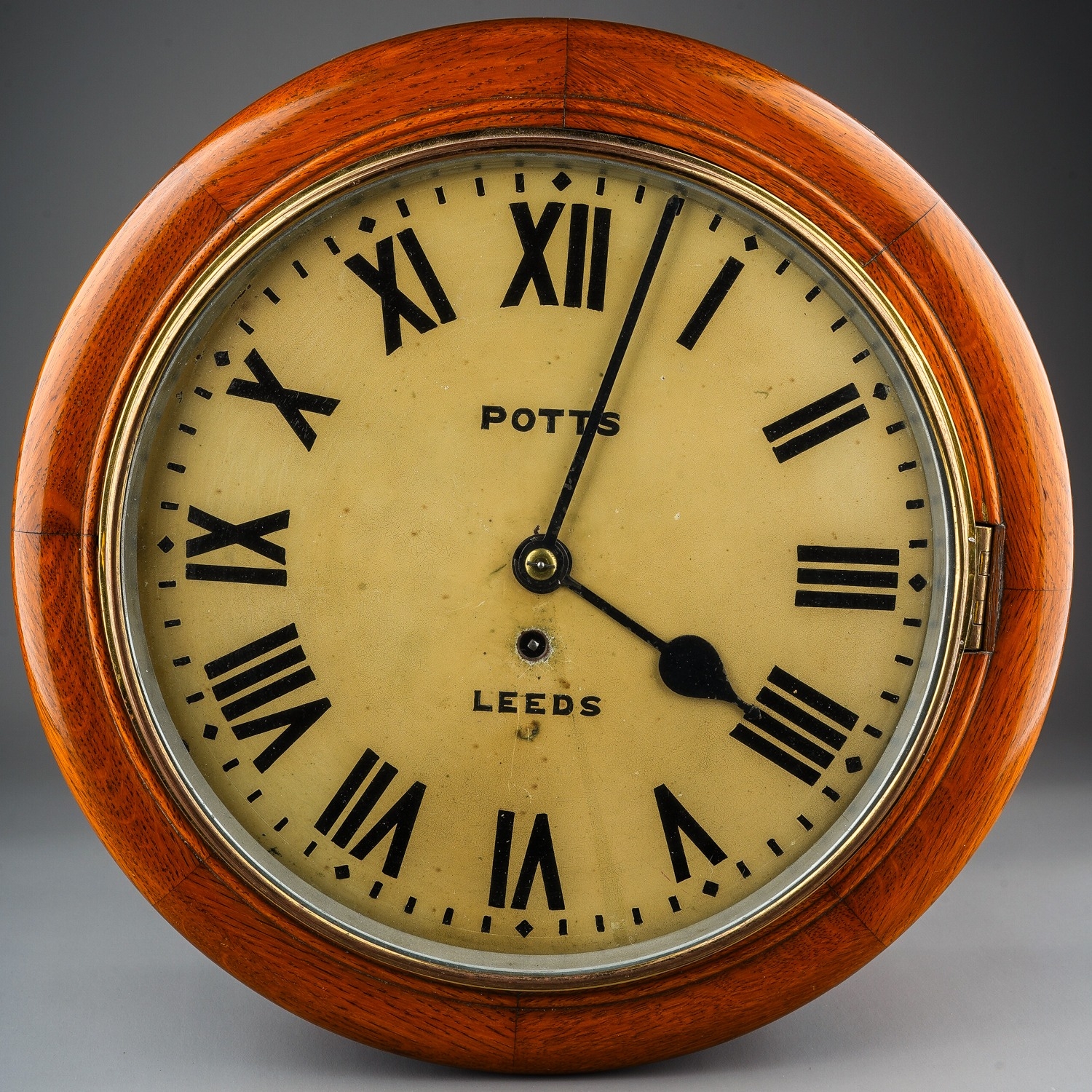 Wall Clock by Potts of Leeds in a wooden mahogany case, with Roman numerals on the dial.