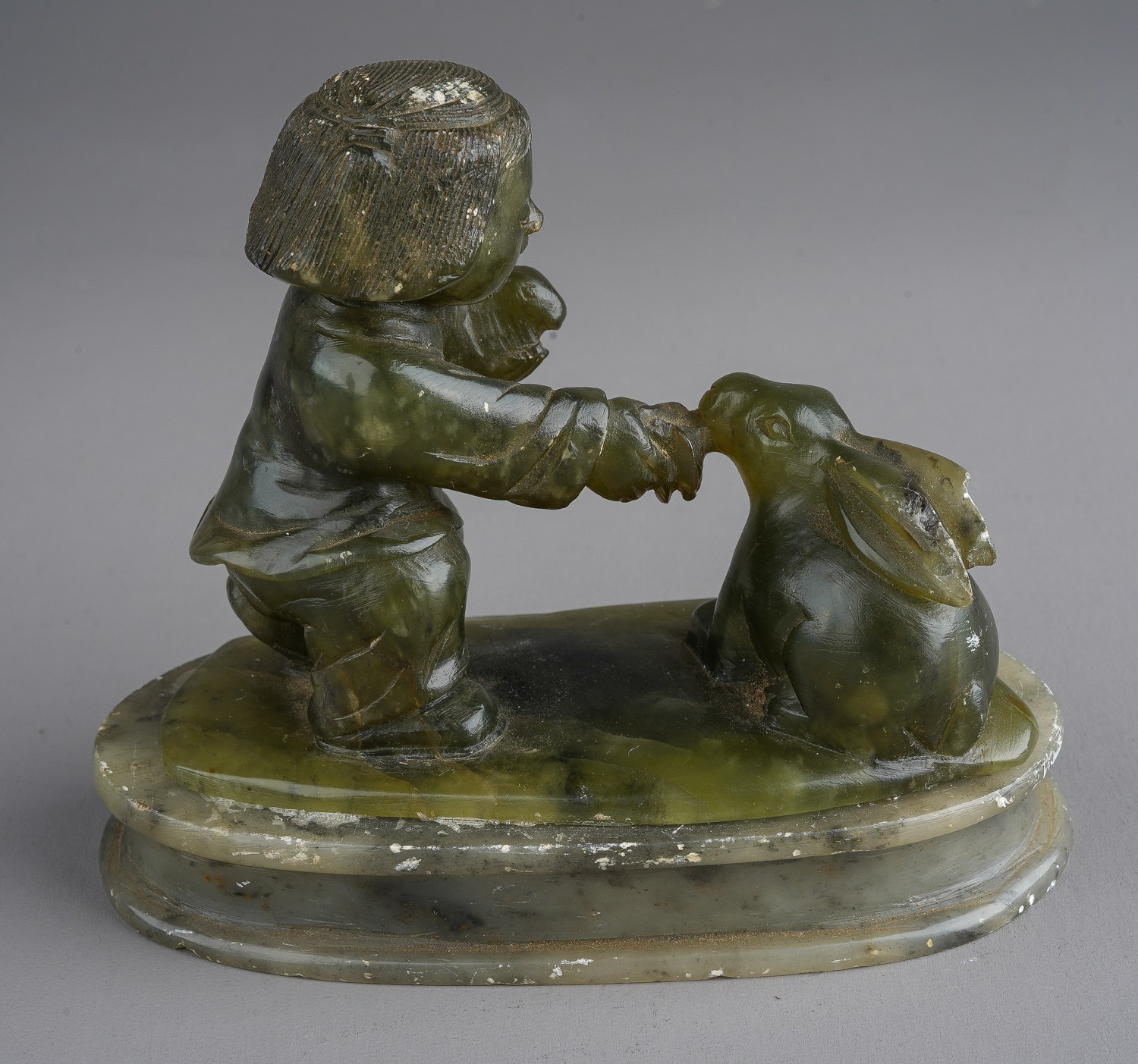 A nephrite coloured carved figure of boy holding a rabbits on an oval plinth base damage to larger - Image 2 of 2