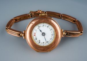 A 1930s 9ct rose gold watch, white enamel dial with Arabic numerals, integral expanding 9ct stap,