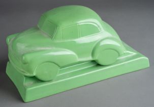 A Dartmouth style desk model of ceramic green Morris Minor 1000 on separate stand with recess for