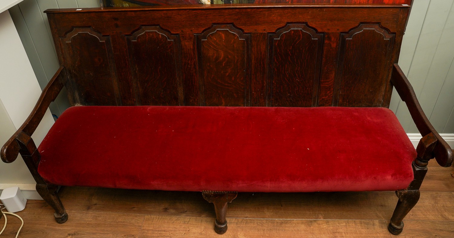 A Victorian style stained oak carved settle, the back rest with geometric sections above red
