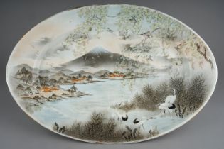 An early 20th Century Japanese Export oval earthenware dish, the entire painted with river landscape