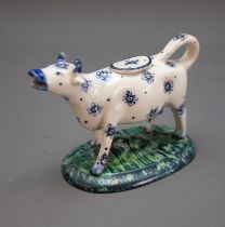 An 18th Century style cow creamer, decorated with blue stylised flowers on oval base with striated