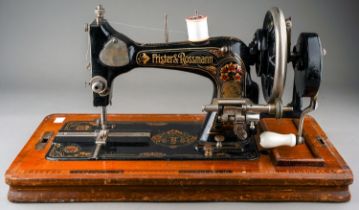 An early 20th Century cased Frister & Rossman black and gilt cranked sewing machine, the stand
